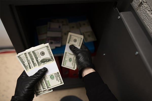 person stealing money from safe wearing gloves