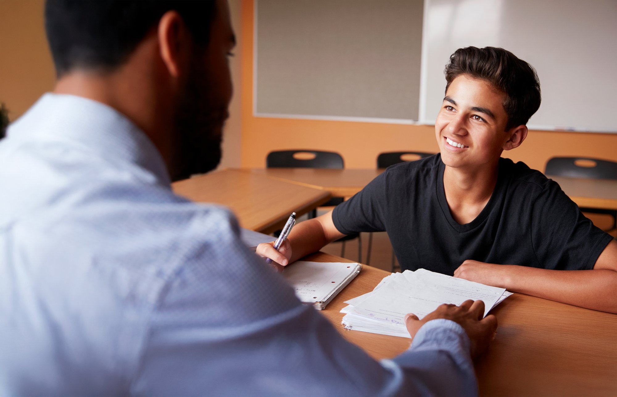 Adult tutor giving feedback to young male student