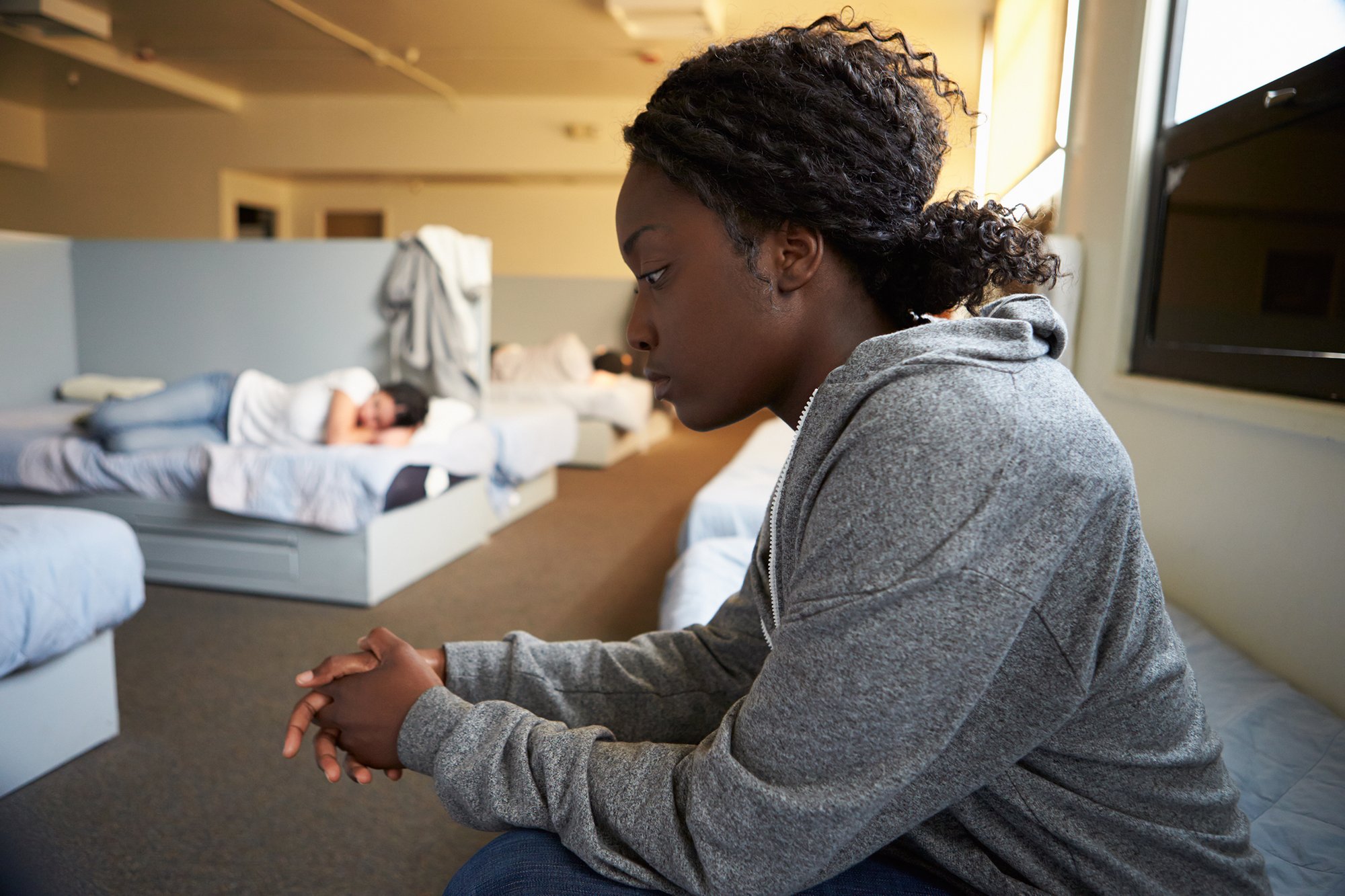 Woman sitting on a bed in a housing shelter